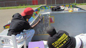 Leerlingen drukken een tekening met behulp van houtskool door op een skatetoestel 