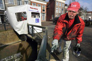 Terwijl Wiepie Nijboer in de tent de verf van de brugleuning krabt zet zijn collega Ame Kooistra het houtwerk in de grondverf